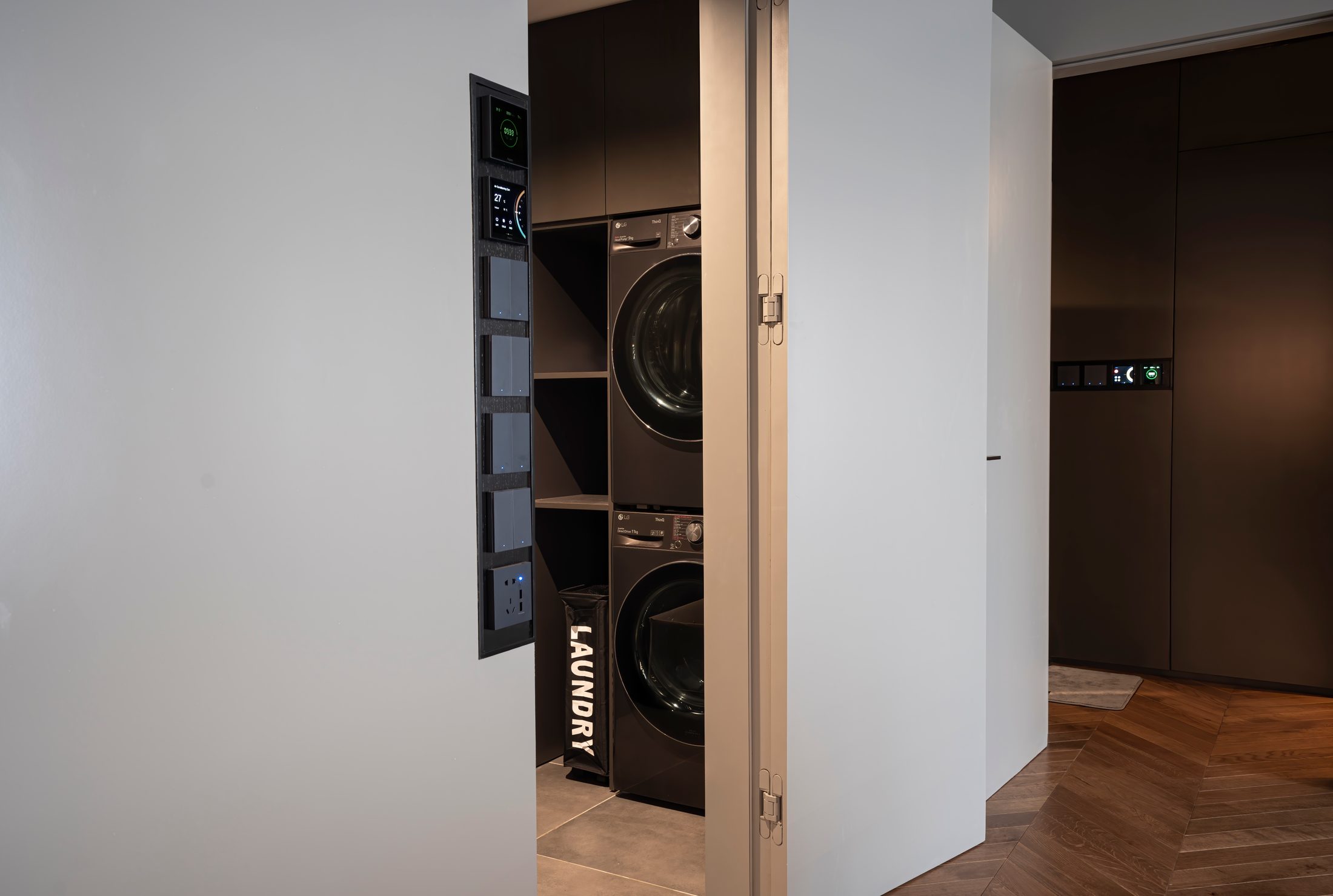 Khu giặt là với máy giặt và máy sấy xếp chồng, giấu sau cánh cửa gập, MM Apartment